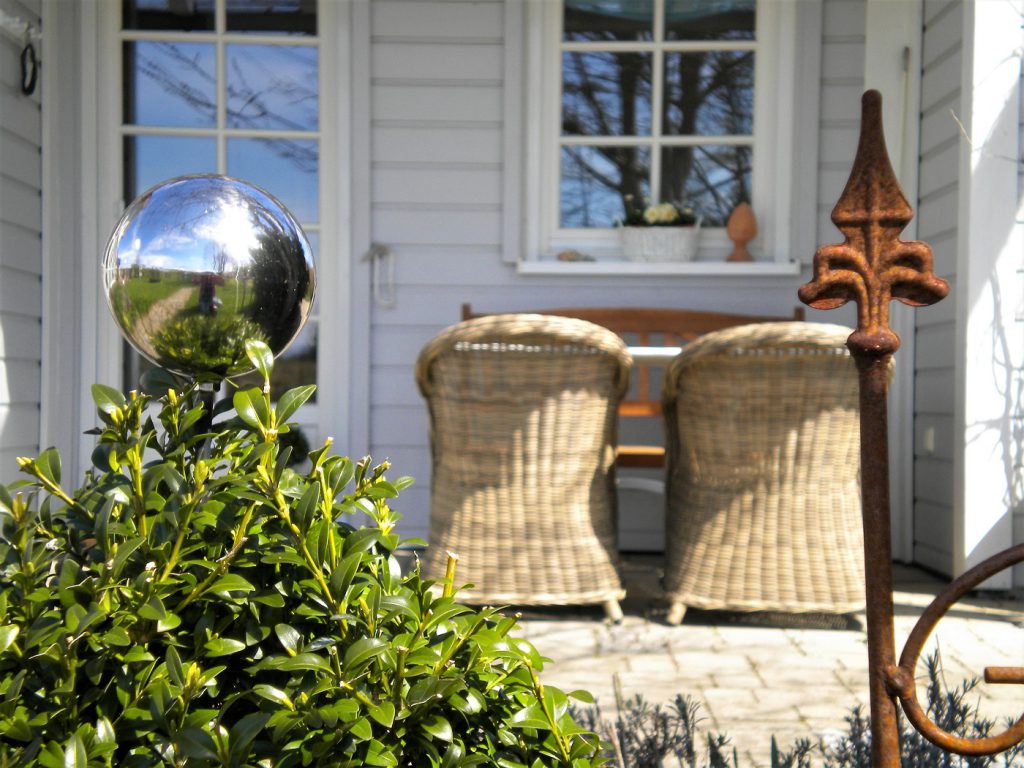 Gartendeko und Korbsessel auf der Terrasse