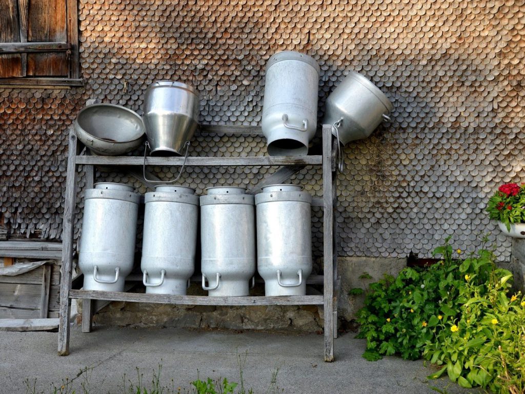Michkannen vor einem Allgäuer Berg-Bauernhof